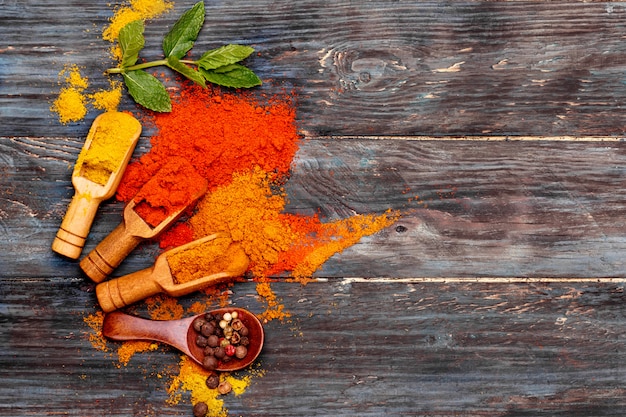 Colorful spices in wooden spoon on wooden background