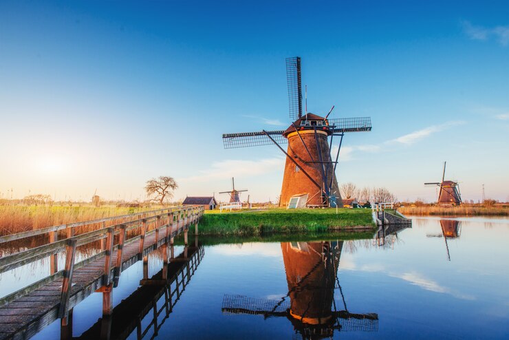 Photo colorful spring day with traditional dutch windmills canal in rotterdam. wooden pier near the lake shore. holland.