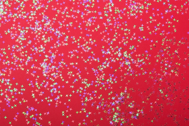 Colorful star confetti on red surface