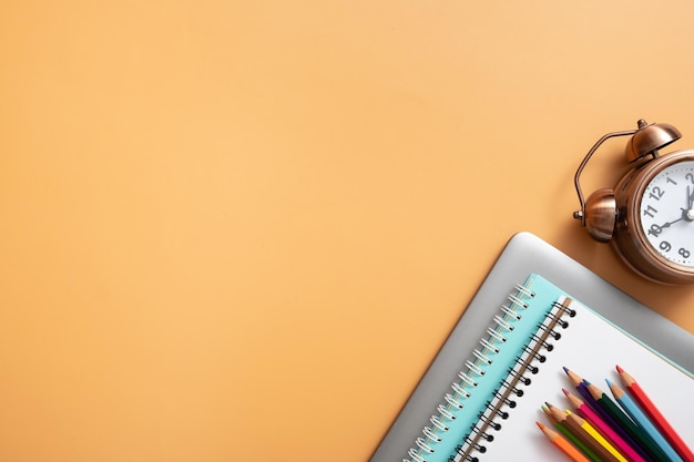 Colorful stationary and laptop with alarm clock on colored background Copy space Children work space top view flat lay Online learning concept