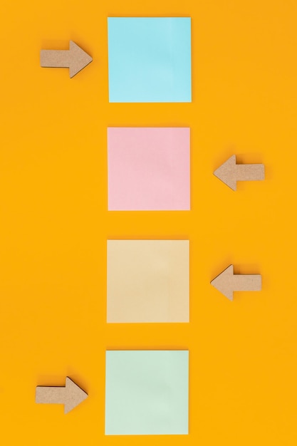 Colorful sticky notes and different wooden arrows on yellow background