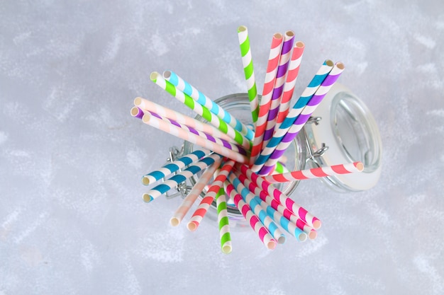 Photo colorful striped paper disposable tubes in a jar on a gray background