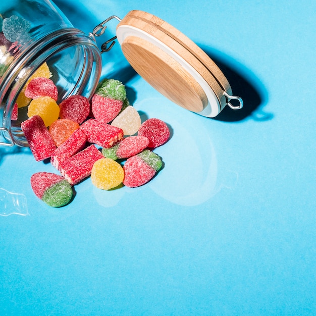 Фото Красочные конфеты сахарного меда, разливаясь из банки на синем фоне