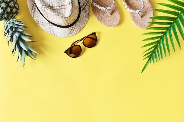 Colorful summer composition with straw hat sunglasses palm leaves pineapple and flip flops