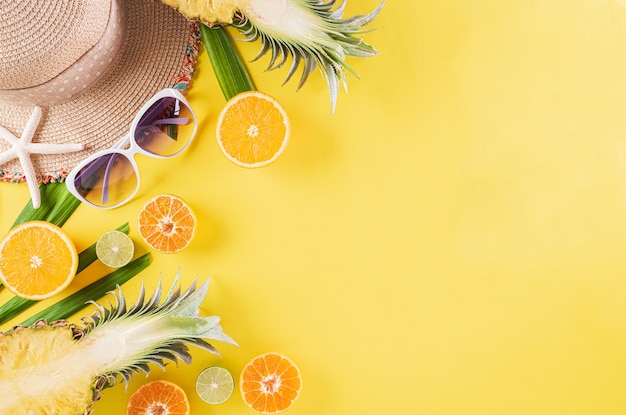 Colorful summer and holiday concept, Straw hat, sunglasses, palm branches, pineapple and star fishon yellow background.