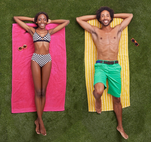 Colorful summer vibes A young african couple lying on the grass together