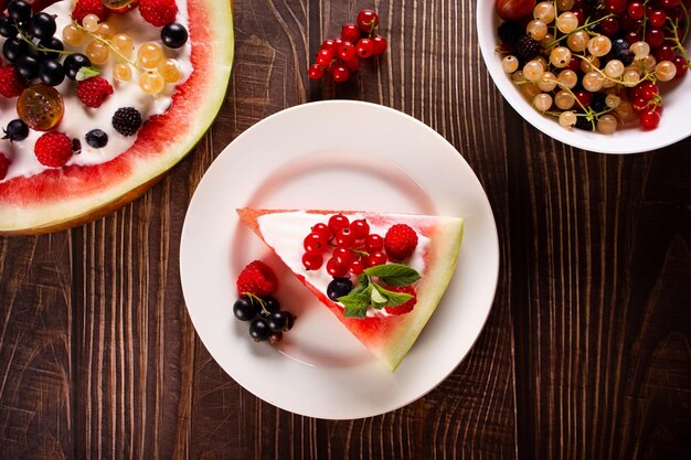 Colorful summer watermelon piece of cake with whipped cream and berries