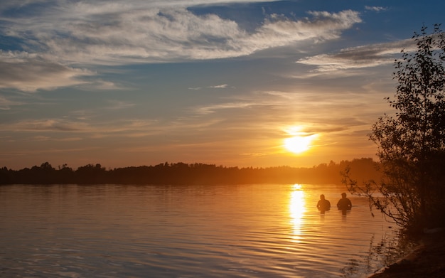 穏やかな湖に沈む夕日。太陽は水面に反射します。