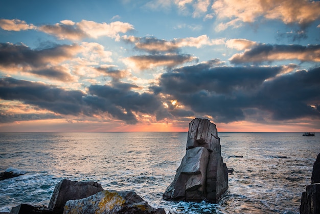 Colorful sunrise over rocky beach.