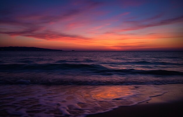 A colorful sunset over the ocean with a pink sky and the sun setting behind it.