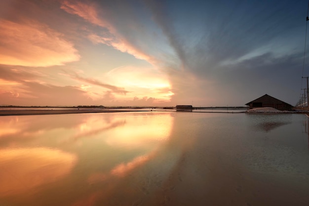 Colorful sunset sky and its reflection of a salt farm