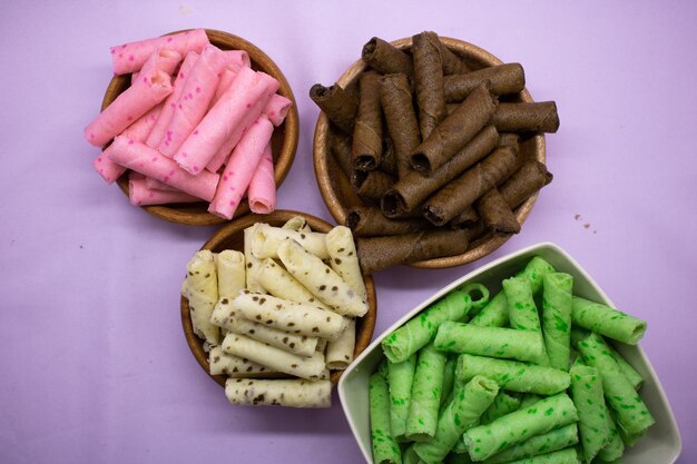 Colorful sweet wafer cream rolls isolated on violet background