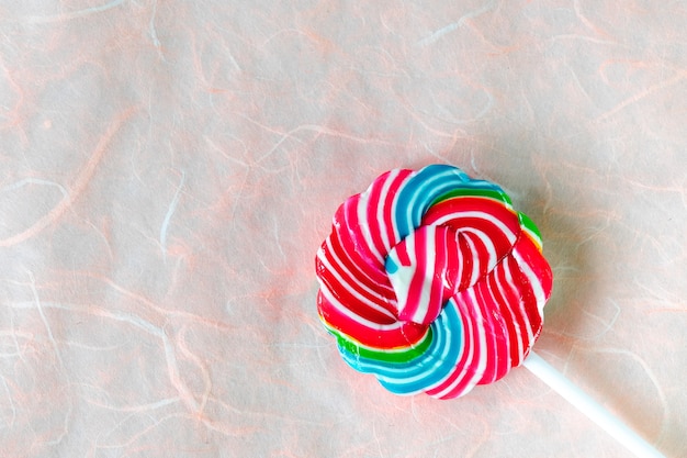 Colorful swirl lollipop  on mulberry pink paper background. Minimalism Creative view 