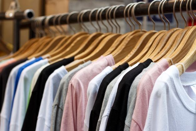 Colorful T-shirts on wooden hangers in store