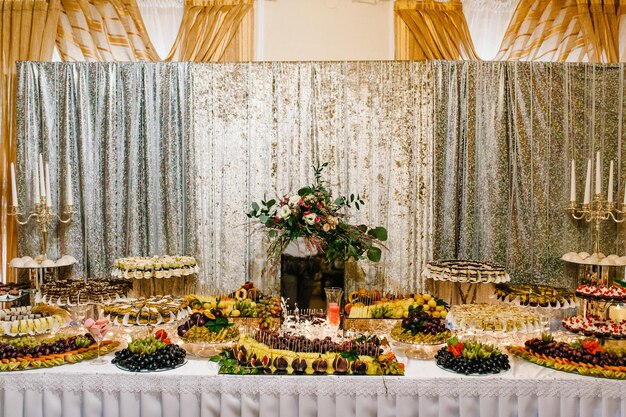 Colorful table with sweets and goodies for the wedding party reception, decorated dessert table. Delicious sweets on candy buffet. Dessert table for a party. cakes, cupcakes.