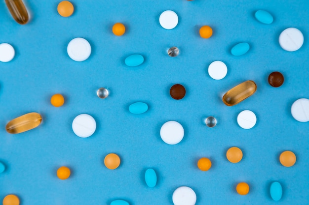 Colorful tablets with capsules and pills on blue background. Top view