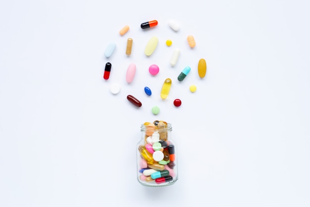 Colorful tablets with capsules and pills on white.