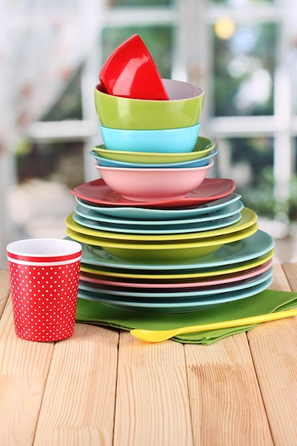 Colorful tableware on wooden table on window background