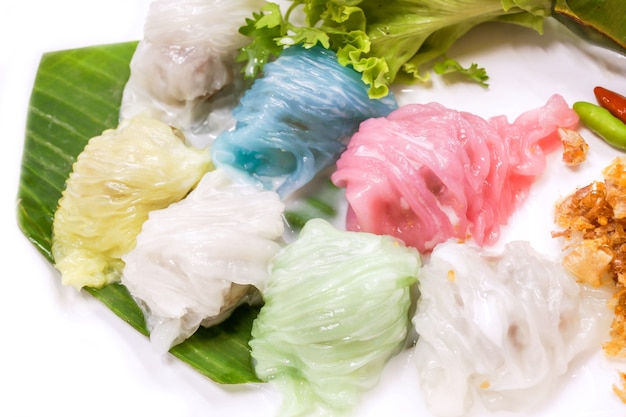 Colorful thai steamed rice skin dumplings (thai popular\
dessert) with coconut milk on top for added flavor on with\
background.