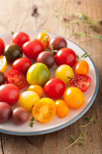 Colorful tomatoes in plate on wooden background