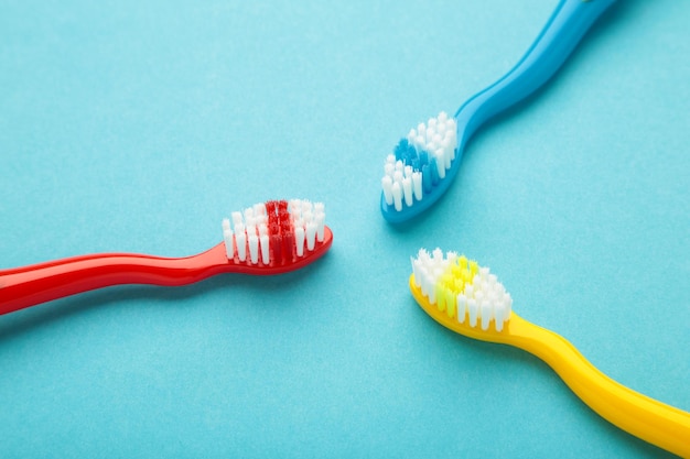 Colorful toothbrushes on blue background Top view