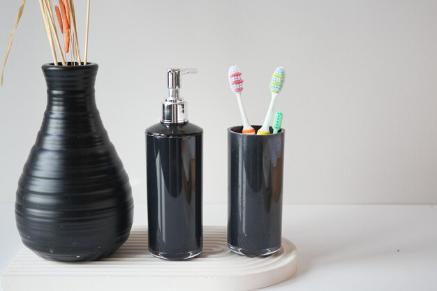 Colorful toothbrushes in white mug against a wall