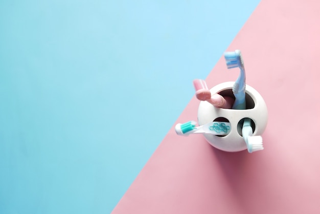 Colorful toothbrushes in white mug against a wall