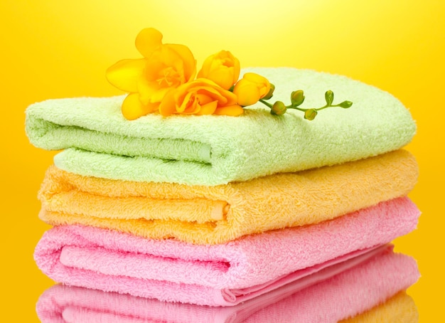 Colorful towels and flowers on yellow background