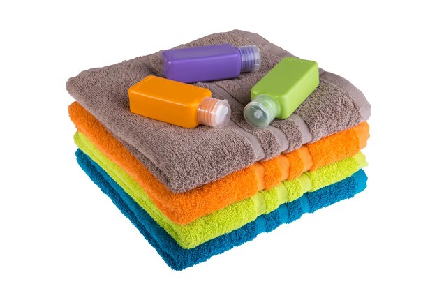 Colorful towels and small plastic bottles for travel on a white background