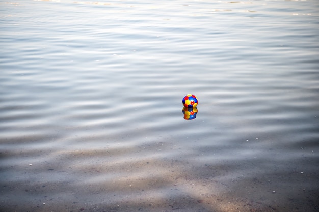 다채로운 장난감 공, 푸른 물결 모양의 물에 반영 축구 게임 속성. 여름 야외 스포츠. 여가와 휴가. 자연과 활동