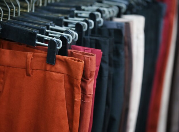 Colorful trousers with hanger on rack