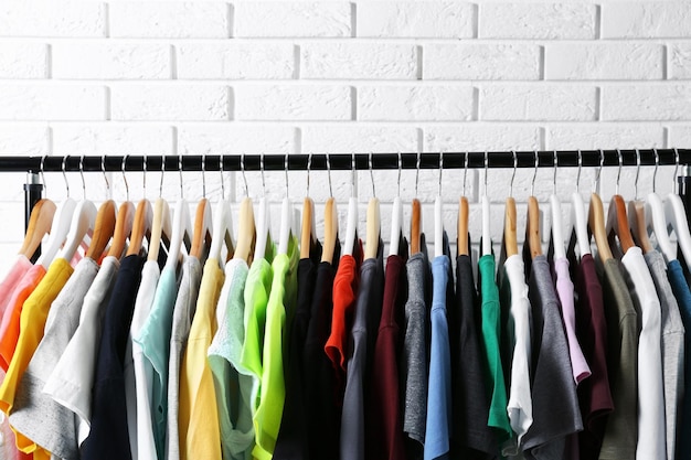 Colorful tshirts on hangers against brick wall