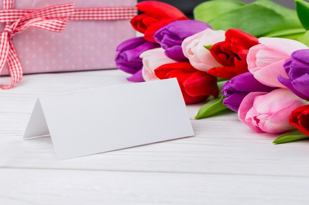 Colorful tulips and white card with present behind