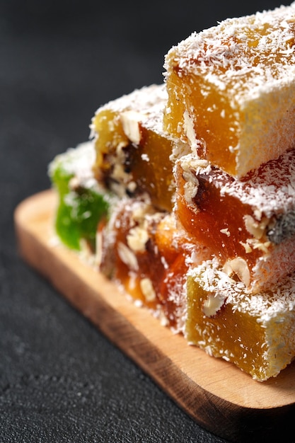 colorful turkish delight stacked on a wooden board with coconut flakes on top