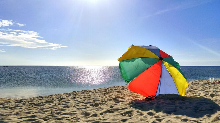 फोटो colorful umbrella at beach against sky on sunny day