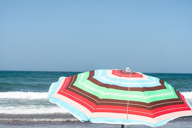 写真 海沿いのビーチでカラフルな傘