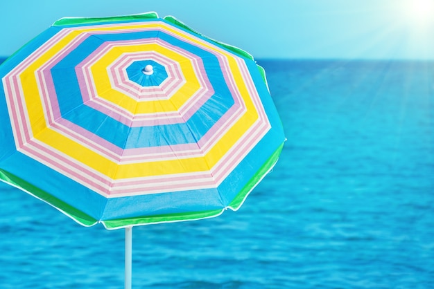 Colorful umbrella on the tropical beach with blue sea and bright sun as background