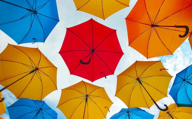 Colorful umbrellas hanging overhead over a blue sky