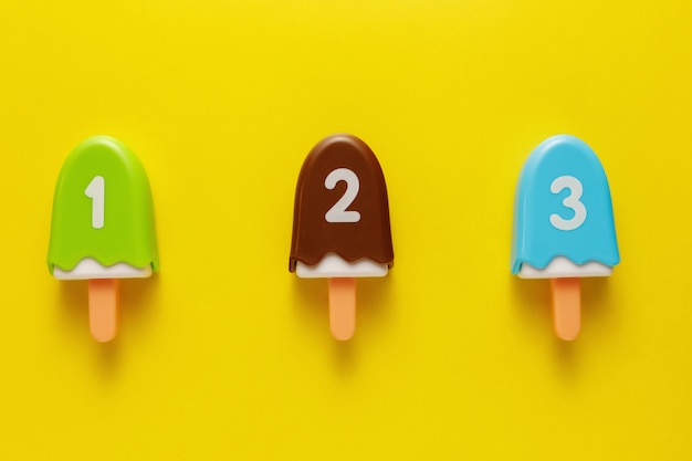 Colorful and various plastic toys ice cream with numbers for babies on a yellow background.