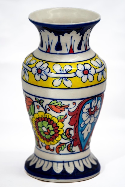 A colorful vase with flowers on it is decorated with a yellow, white, and blue color.