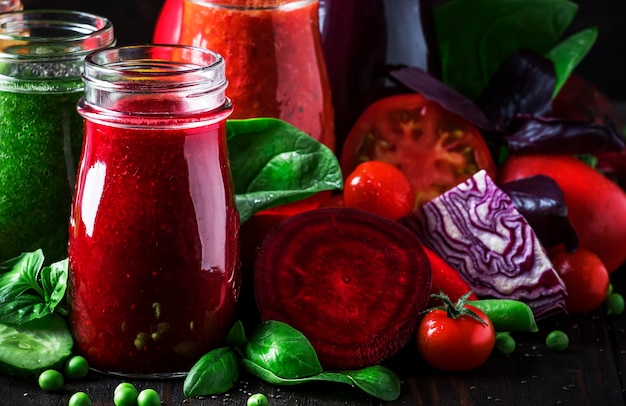 Succhi di verdura colorati e frullati di pomodoro carota peperone cavolo spinaci barbabietola in bottiglie sul tavolo da cucina cibo e bevande vegan fuoco selettivo