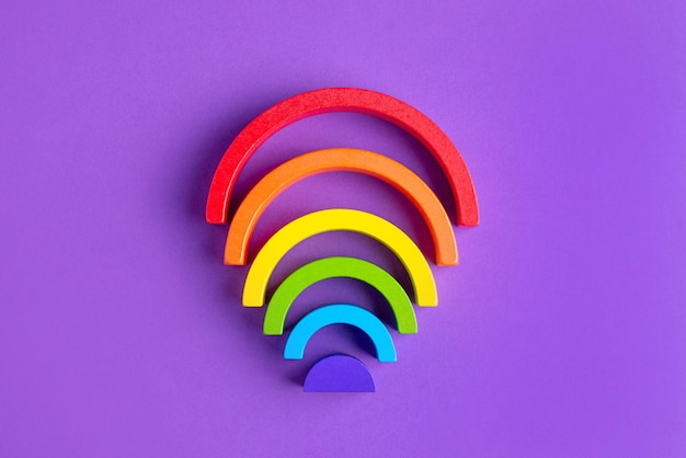 Colorful waldorf wooden human figure rainbow in a montessori teaching pedagogy on purple background