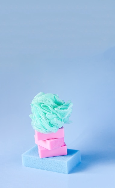 Colorful washcloths and bars of soap on a soft blue background. Accessories for body care and hygiene.