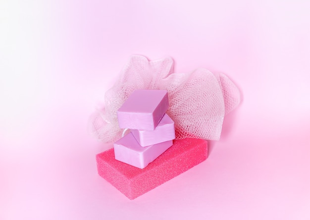 Colorful washcloths and bars of soap on a soft pink background. Accessories for body care and hygiene.