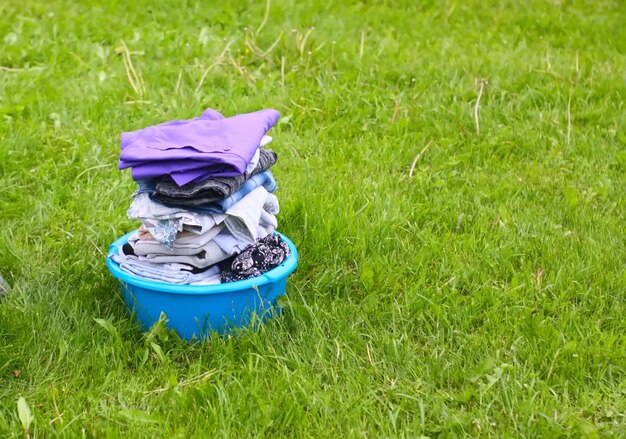 Colorful washed dry clothes in plastic bowl on the green grass background