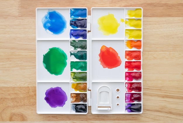 Colorful watercolor paints set in watercolor palette on wood. Bright multicolored aquarelle paints in paint box.