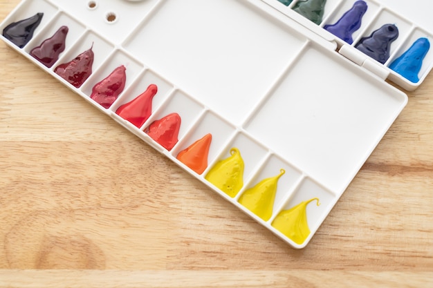 Colorful watercolor paints set in watercolour palette on wood. Bright multicolored aquarelle paints in paint box.