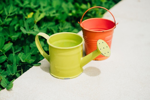 Colorful watering cans and buckets for plants in garden