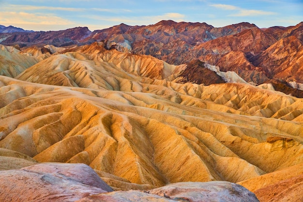 Colorful waves of sediment at sunrise in death valley desert mountains