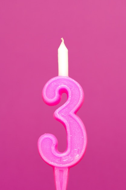 Photo colorful wax birthday candle on pink